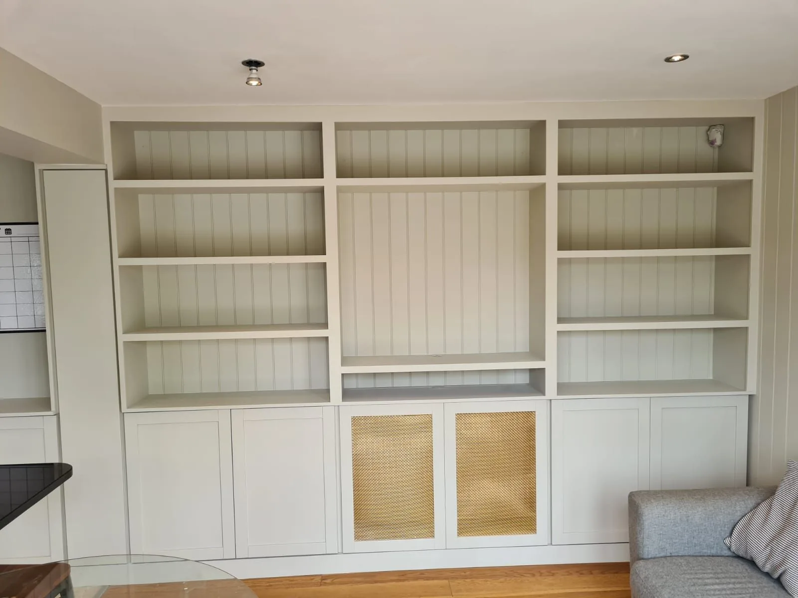 Freshly fitted media wall with open shelving and cane-fronted cabinets
